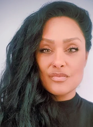 Professional headshot of Syan, wearing a black top, looking confidently at the camera.